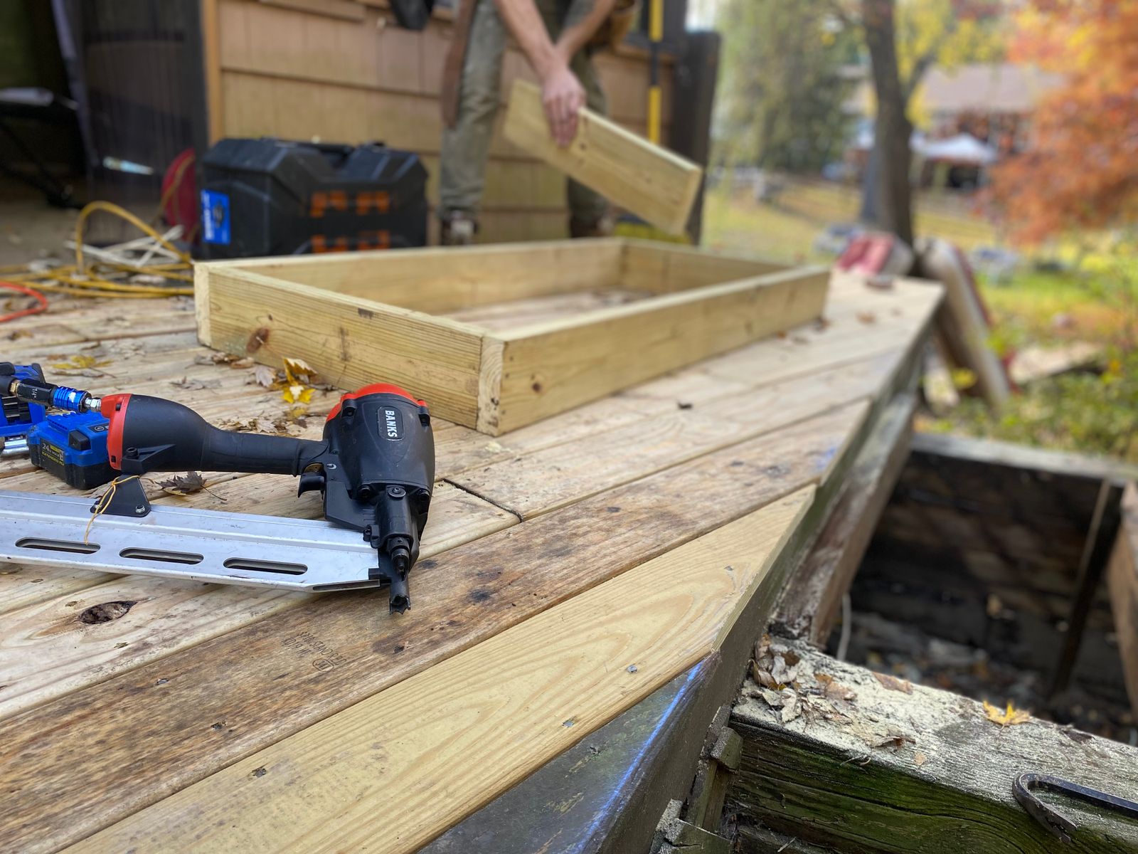 Close-up of carpentry work on a deck with a nail gun and wooden frame under construction — illustrative stock photo, not a photo of Adam or A&A's own work.