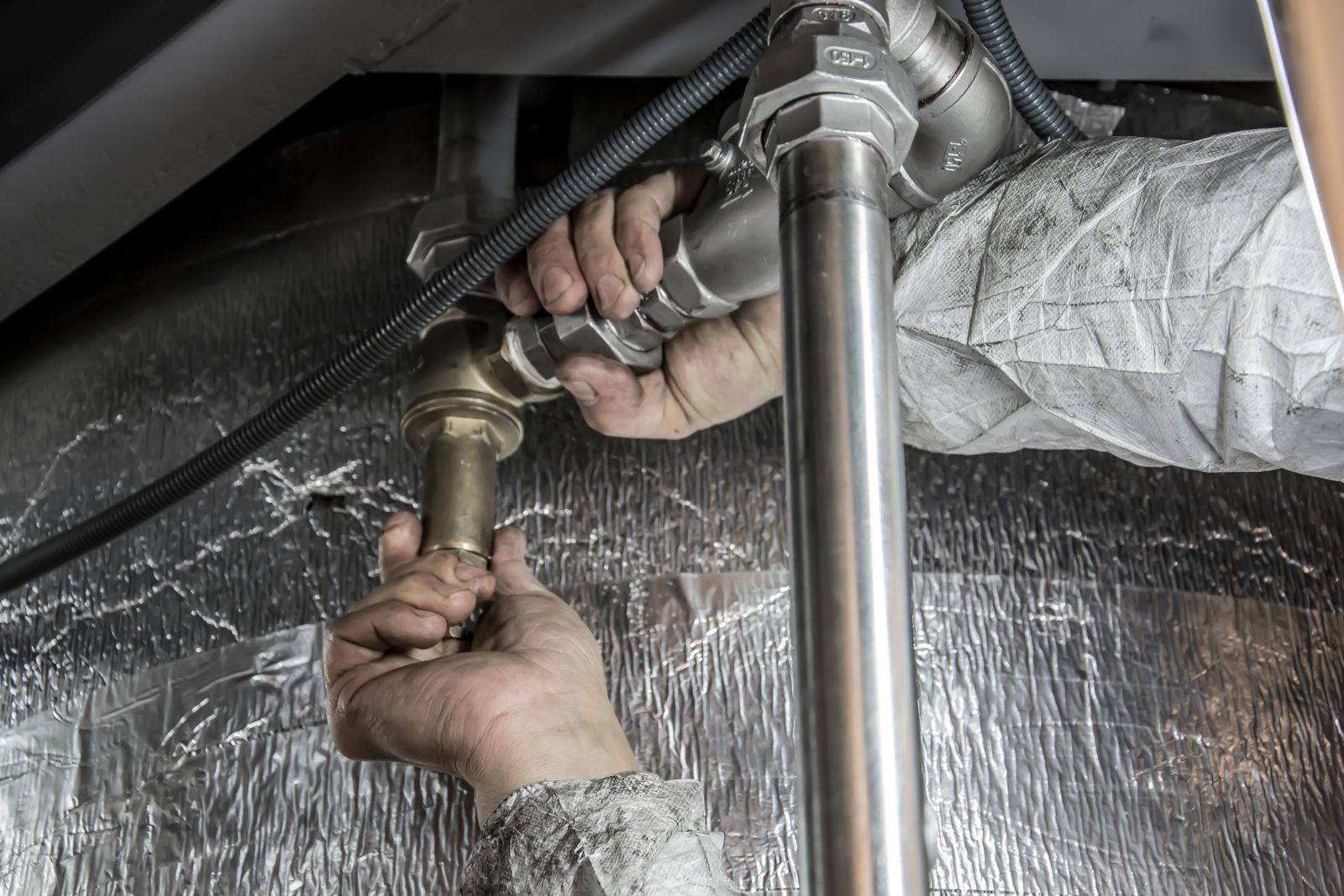 Illustrative stock photo of a plumber installing pipe fittings — not A G Plumbing's own crew.