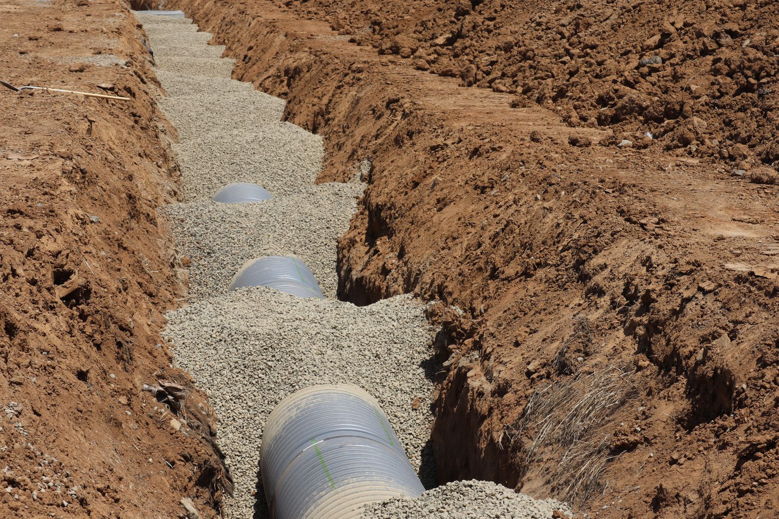 A drainage pipe being installed in a gravel-lined trench — illustrative stock photo, not a photo of All American Septic's own job site.