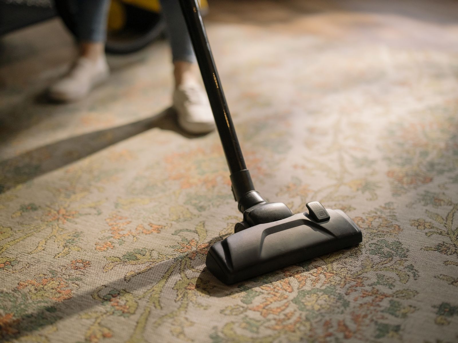A close-up of a vacuum cleaner on a patterned carpet in a sunlit room — illustrative stock photo, not a photo of Allstar Carpet Cleaning or its work.