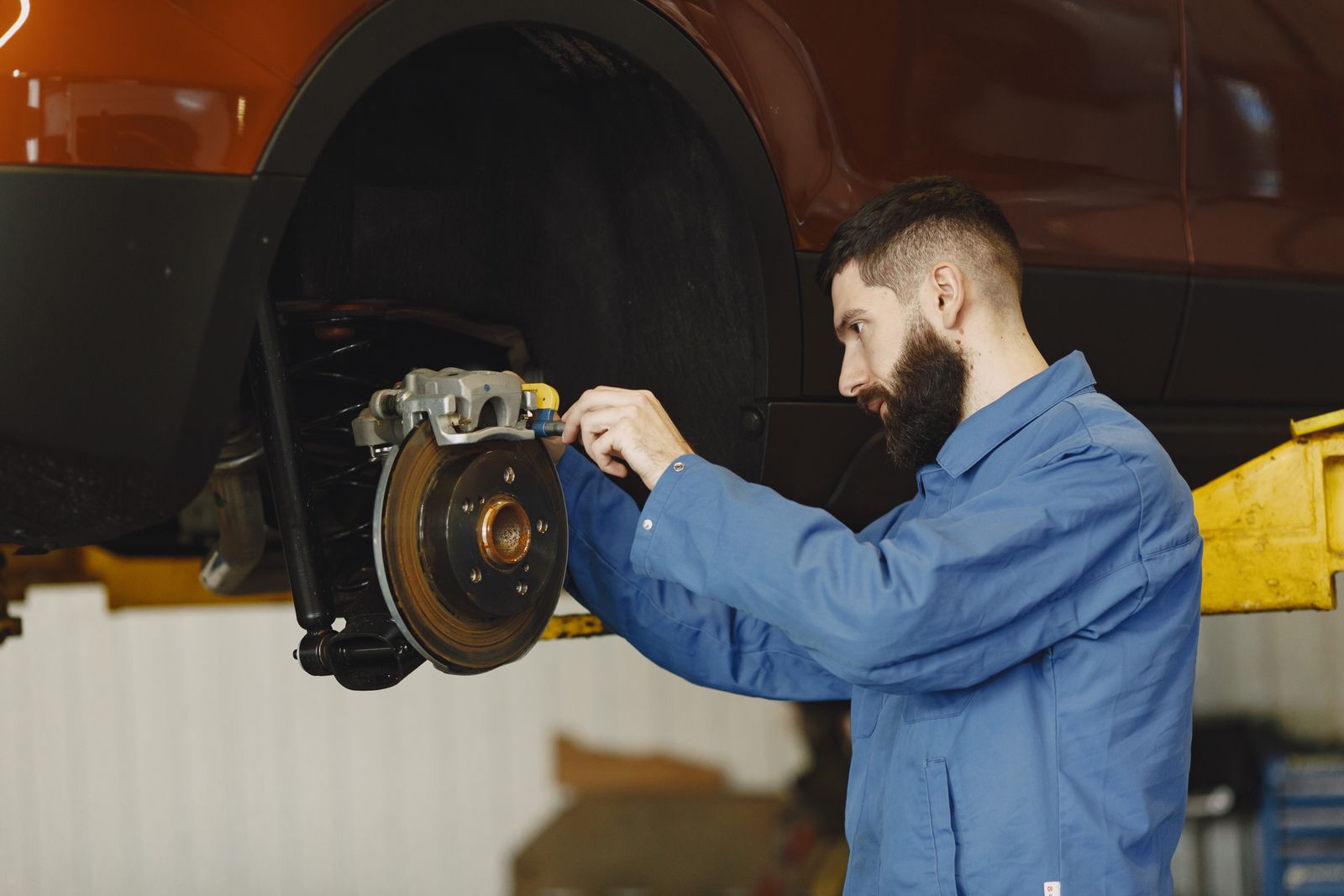 A mechanic inspects a brake caliper and rotor on a lifted car — illustrative stock photo, not a photo of Brazos Valley Automotive or its staff.