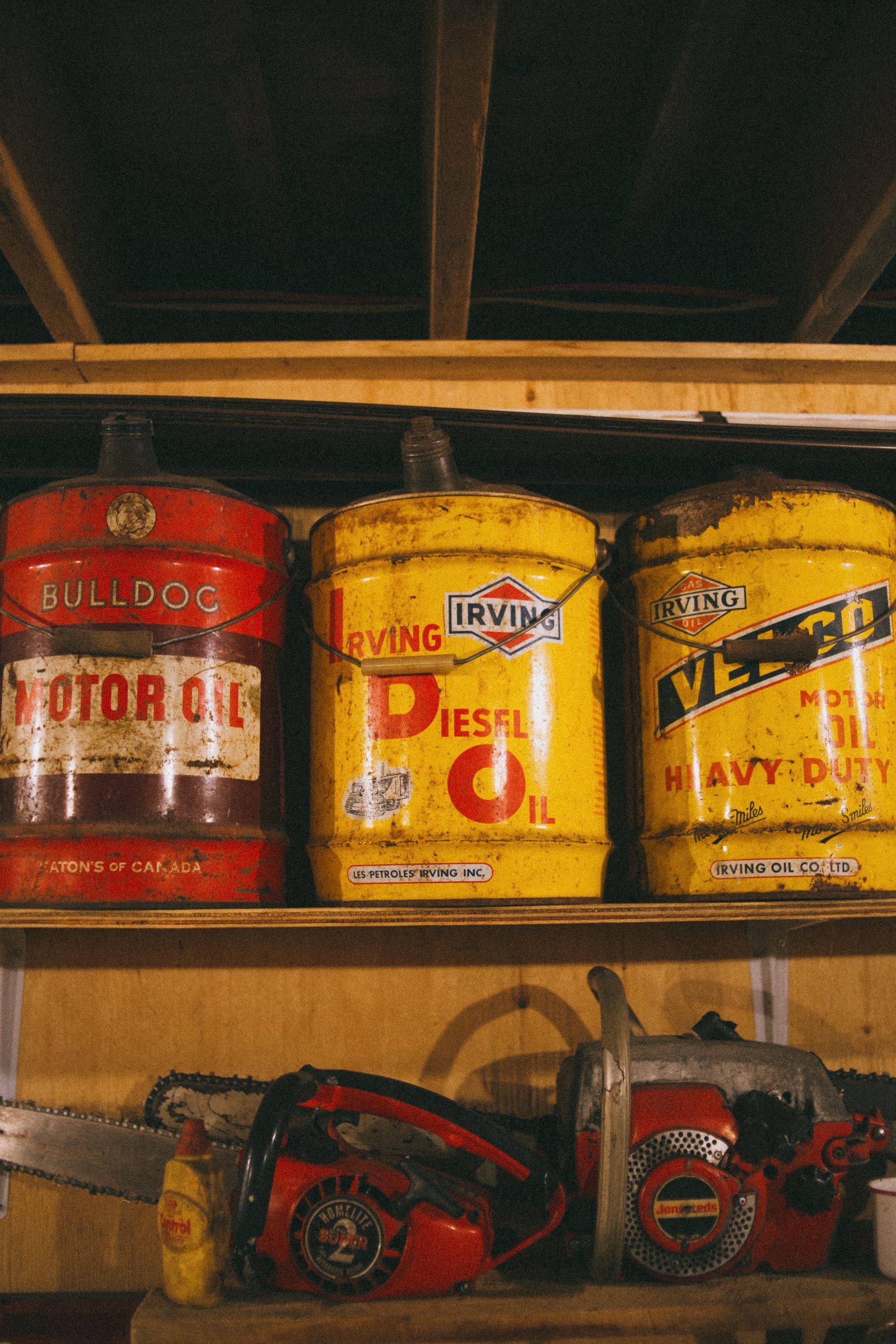 Vintage oil cans and chainsaws displayed on a wooden shelf in a workshop — illustrative stock photo, not Bryan Outboard's own inventory.