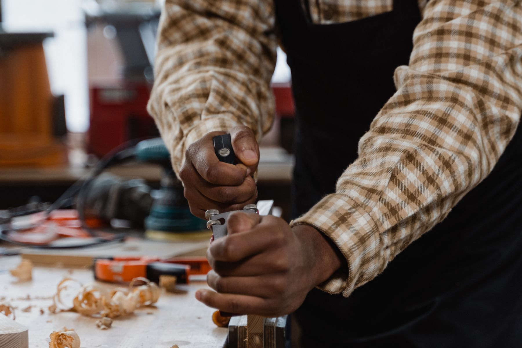 Craftsman's hands using a hand plane on wood in a woodworking workshop, illustrative stock photo