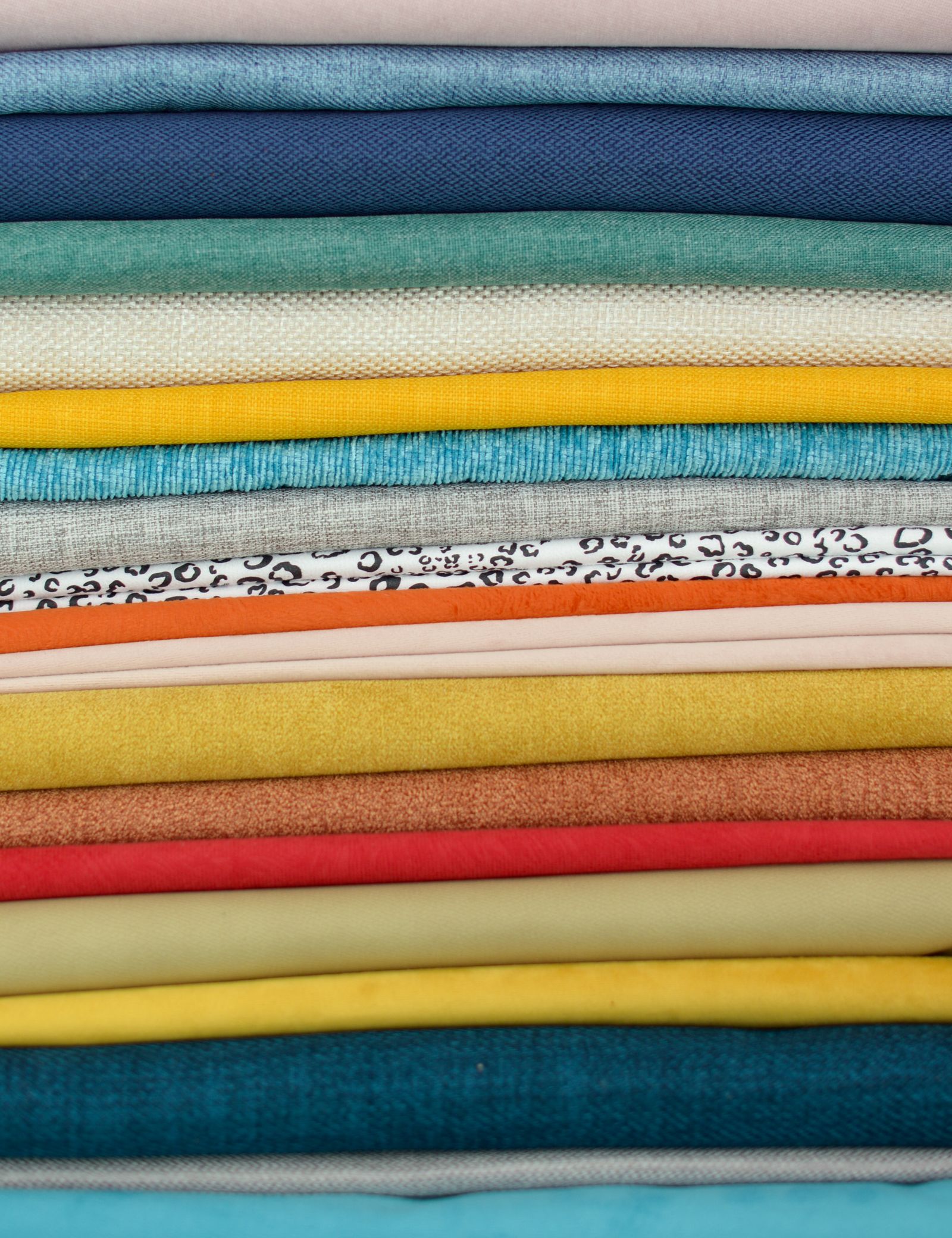 A stack of colorful fabric swatches showing diverse textures and patterns — illustrative stock photo, not Custom Classic's own fabric selection.