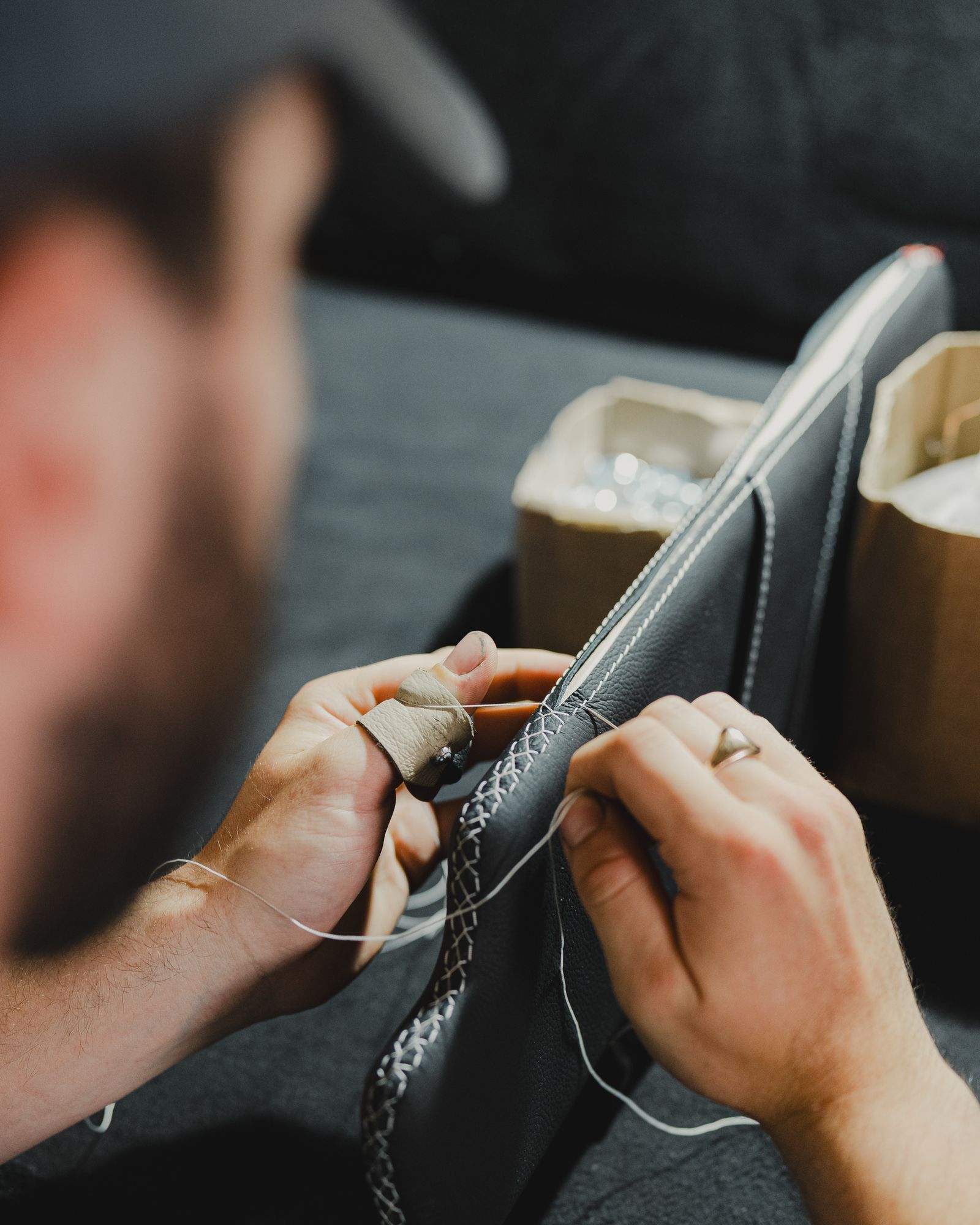 Close-up of a craftsman hand-stitching leather upholstery — illustrative stock photo, not a photo of Custom Classic Upholstery's own work.