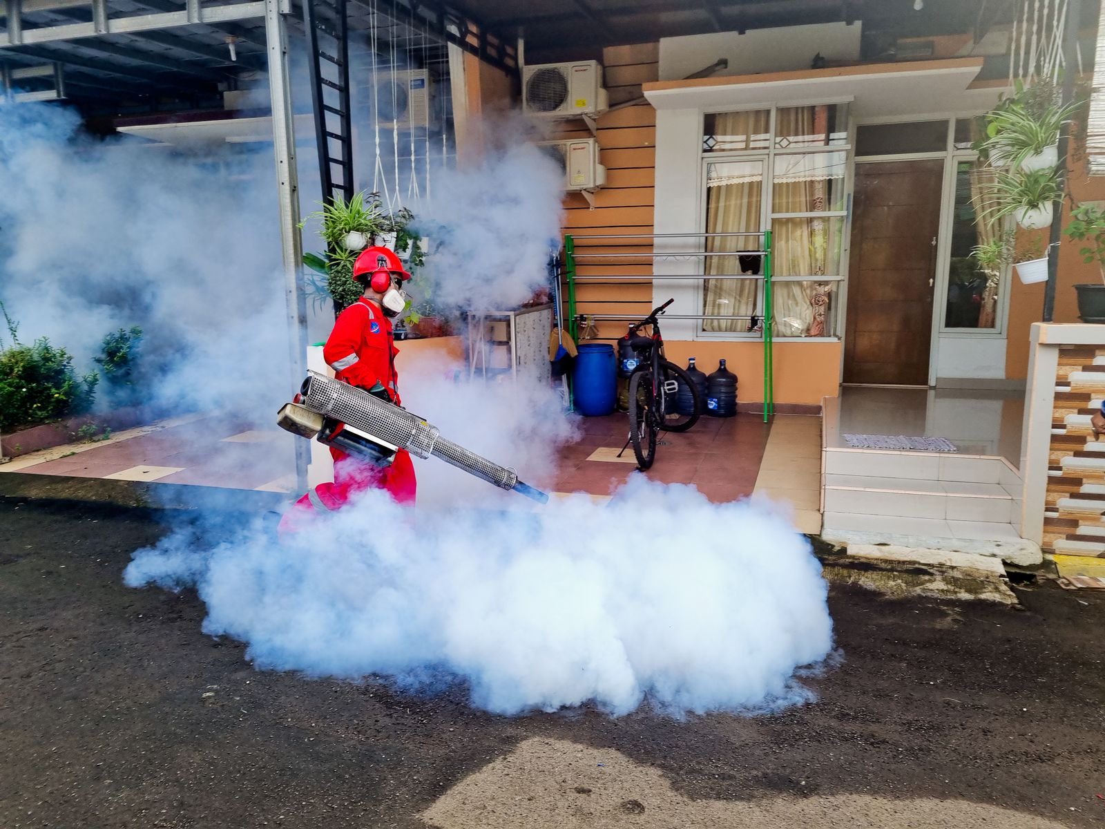 A pest control specialist using a smoke machine to treat the exterior of a residential house — illustrative stock photo, not a photo of Dan or Danomite's own work.