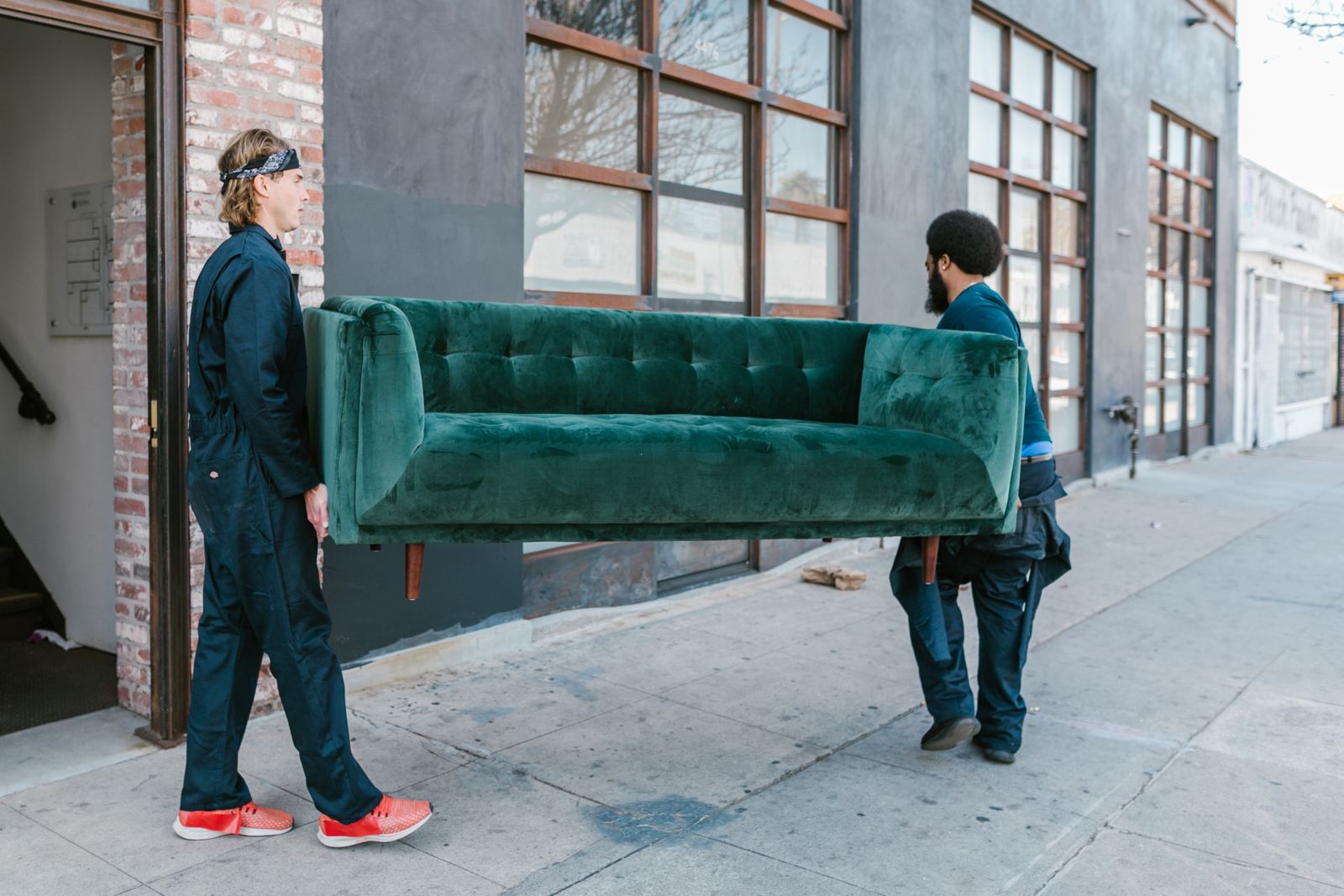Two people carrying a couch together on a city street during a haul-away job — illustrative stock photo, not Feral's own crew.