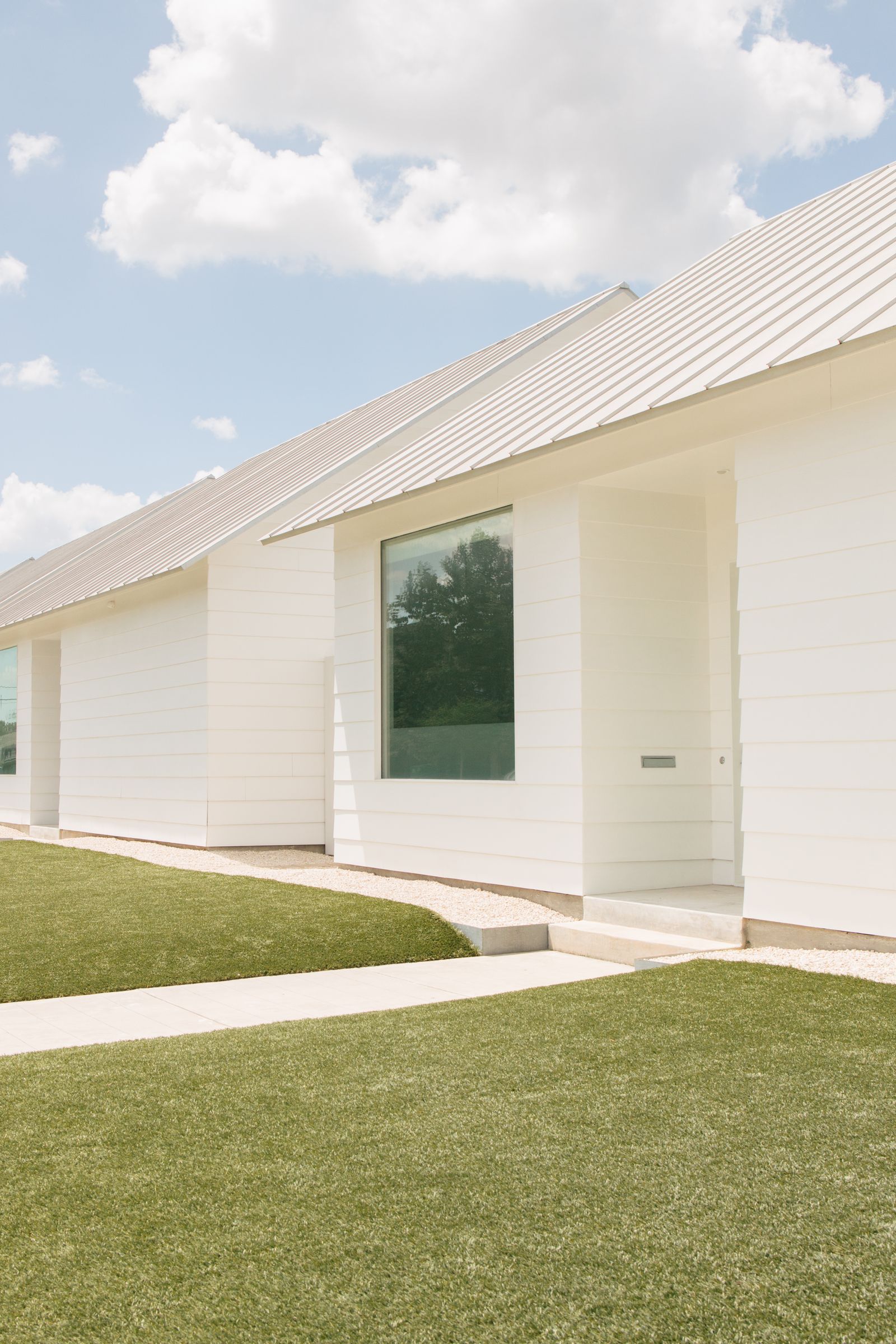 A sunny modern house exterior with large glass windows under a clear blue sky in Houston, Texas — illustrative stock photo, not a Garcia Solar Screens installation.