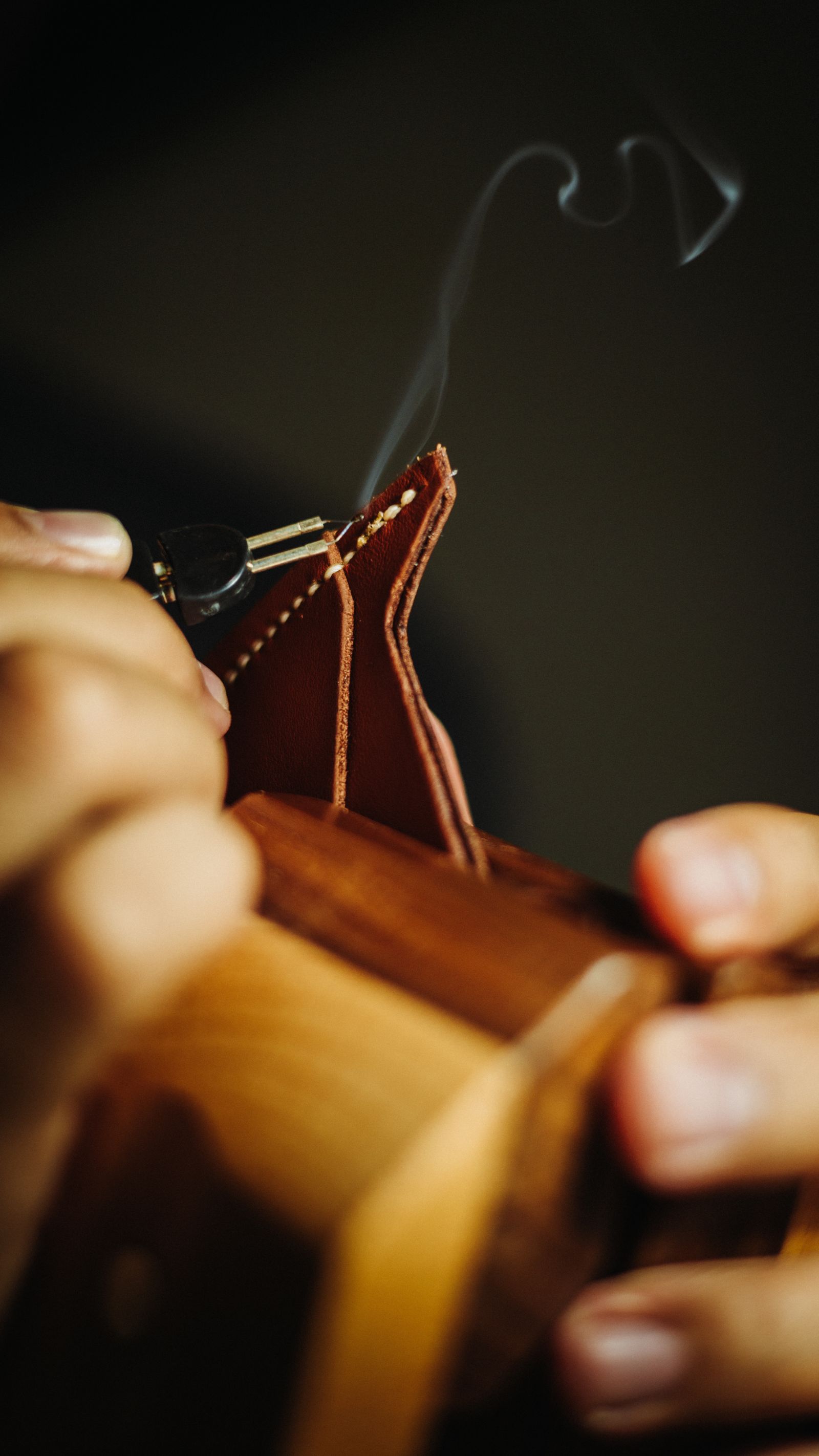 A close-up of a craftsman's hands working leather by hand — illustrative stock photo, not a photo of Gomez Shoe Repair or its staff.
