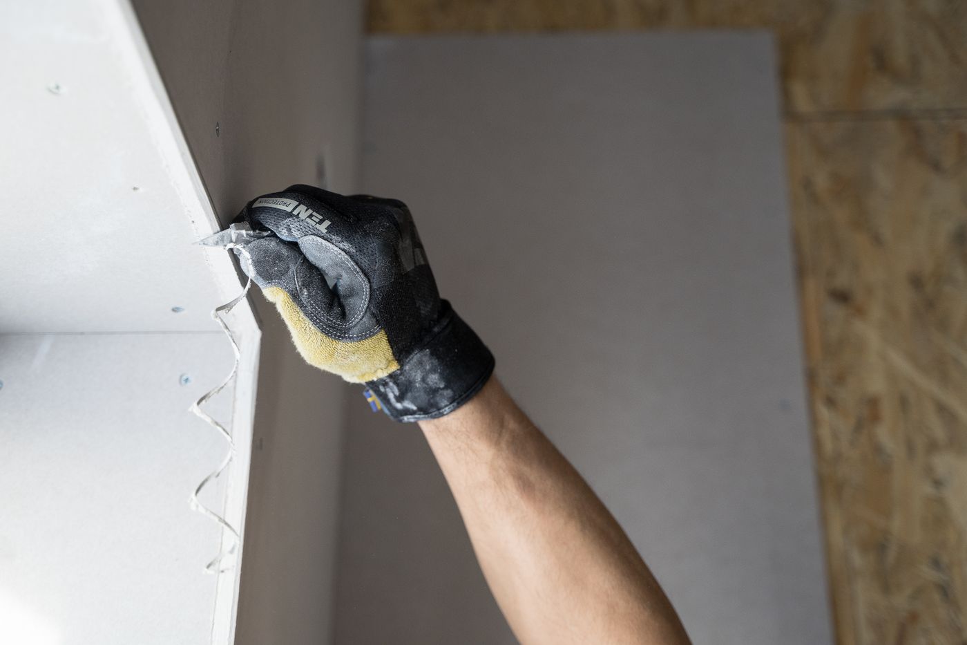 Gloved hand finishing drywall during a repair, illustrative stock photo