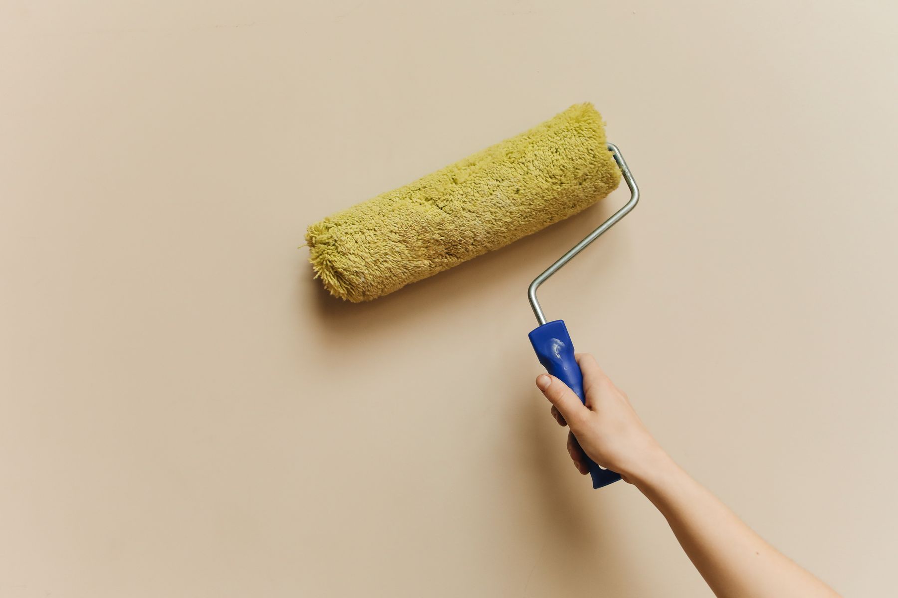 Hand using a paint roller to paint a wall, illustrative stock photo