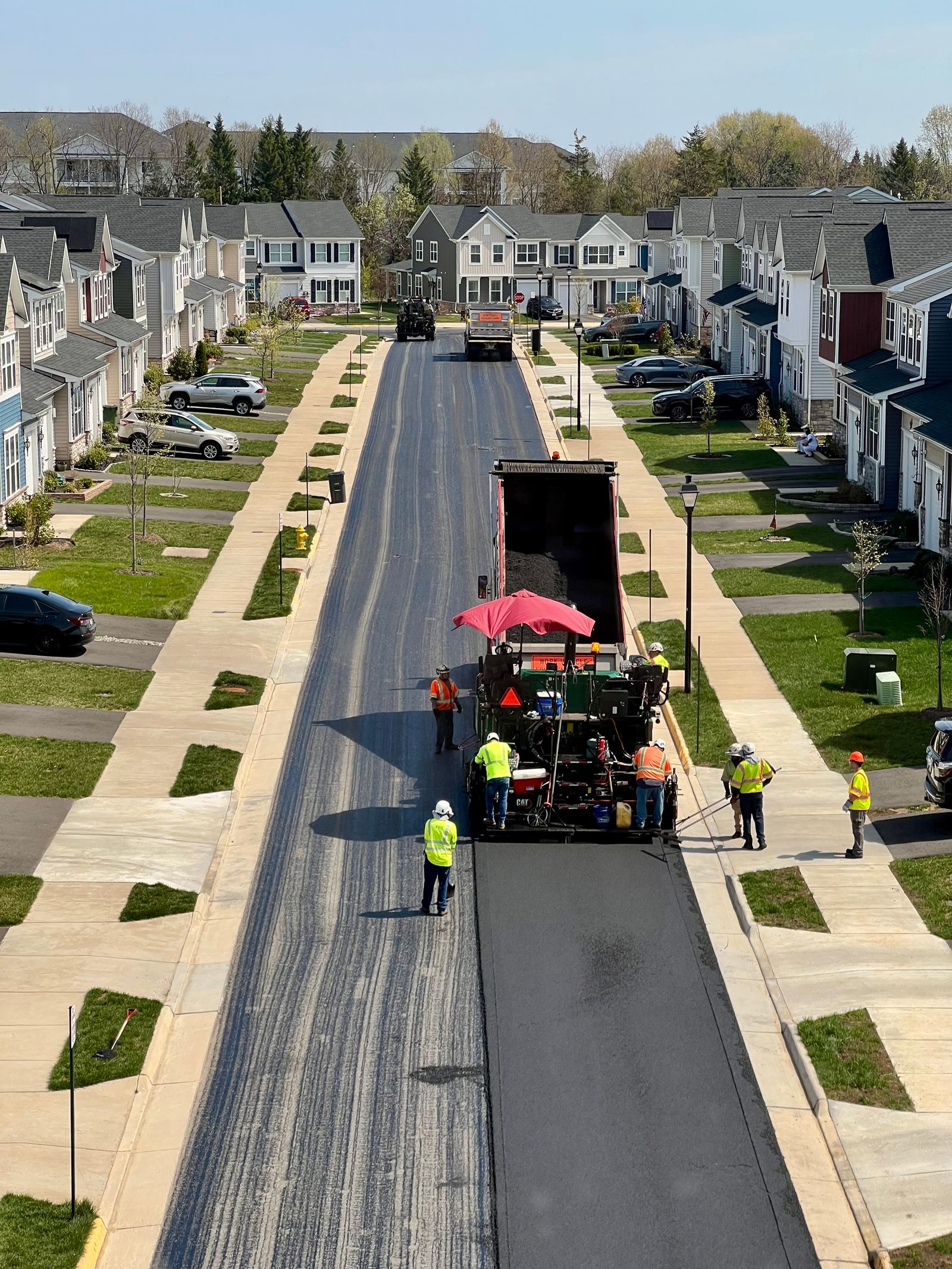 Road crew paving fresh asphalt in a residential neighborhood — illustrative stock photo, not a photo of a J&W Asphalt Paving job.