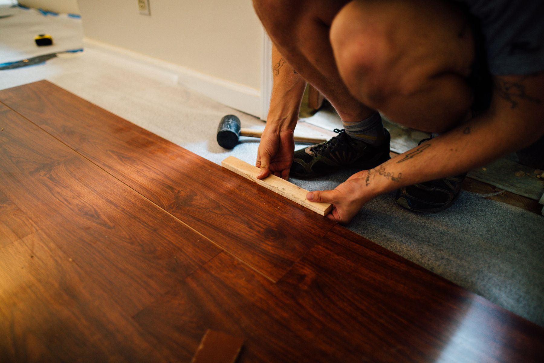 Installer laying laminate/LVP flooring plank by plank, illustrative stock photo