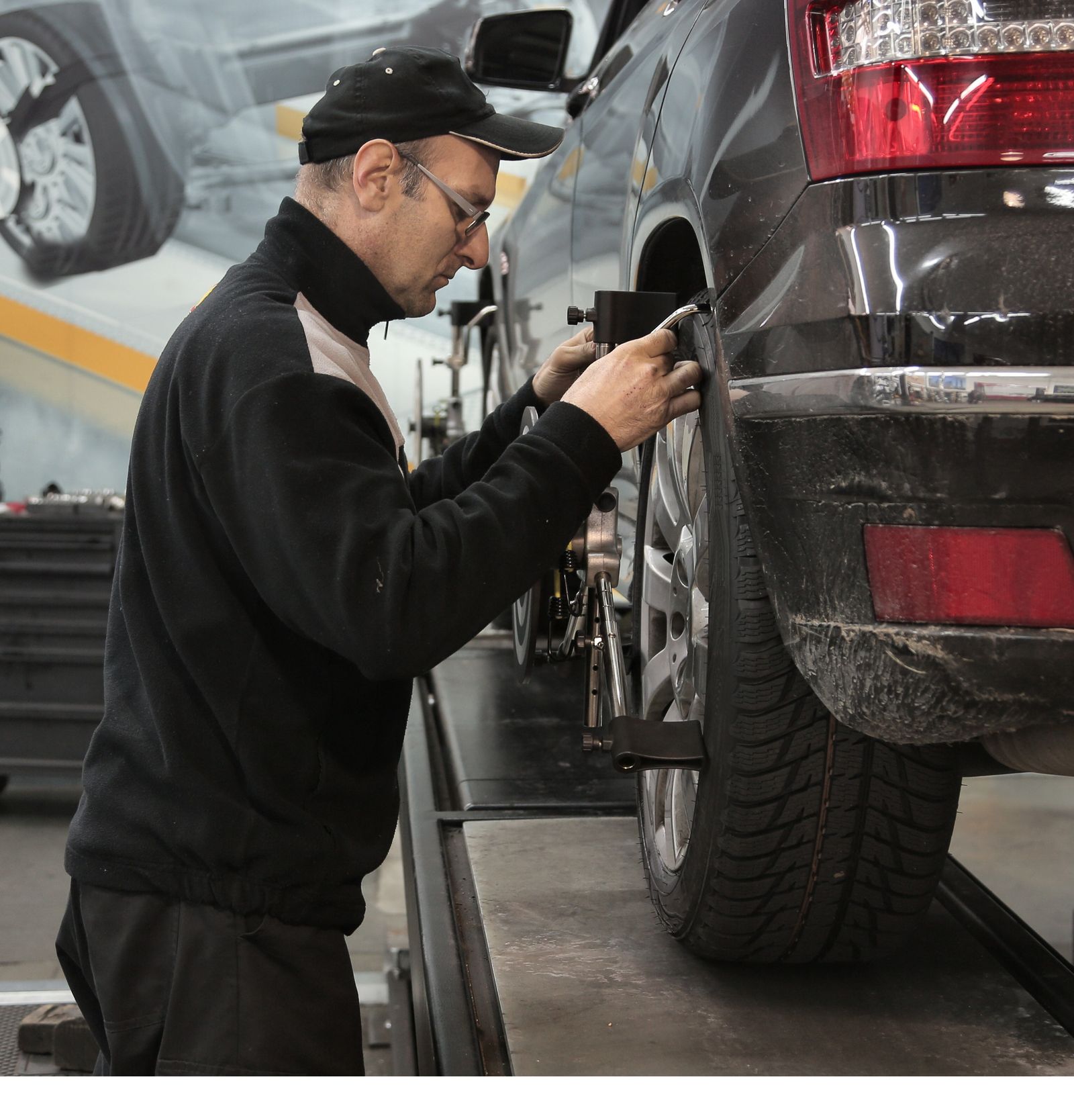 A mechanic adjusting wheel alignment equipment in an auto repair shop — illustrative stock photo, not a photo of Mansel's Wheel Alignment or its staff.