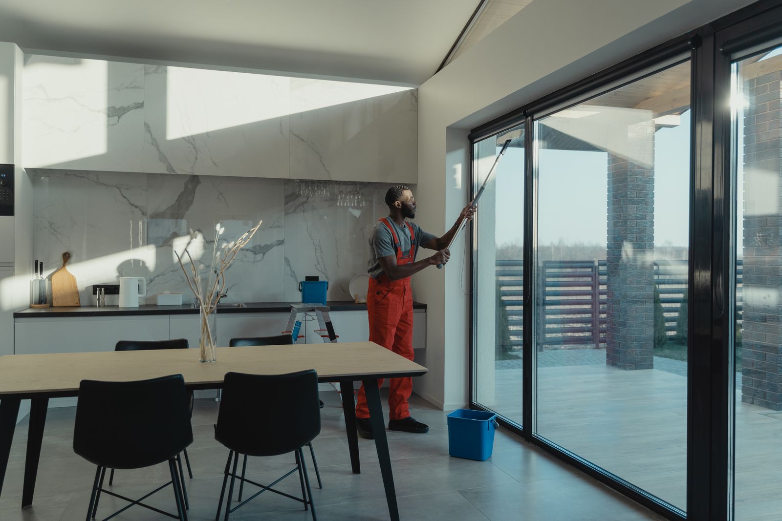 A professional cleaner washing large glass windows indoors with natural light streaming in — illustrative stock photo, not a photo of Maxey Way's own work.