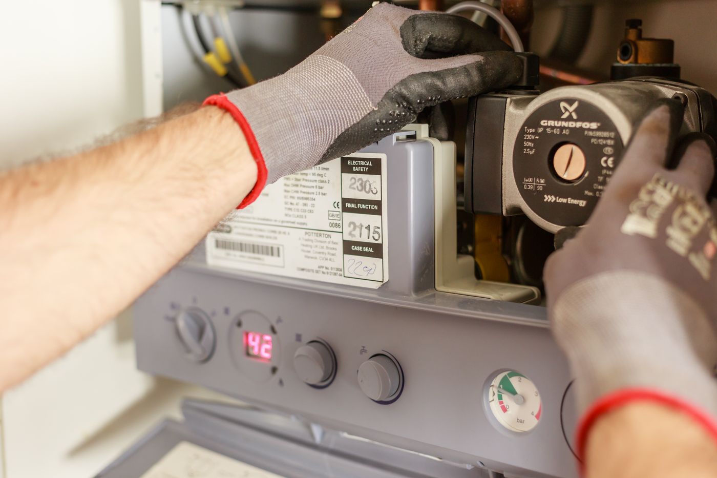 Close-up of hands adjusting a boiler system with precise instrumentation — illustrative stock photo of heating-side work, not Next's own equipment.