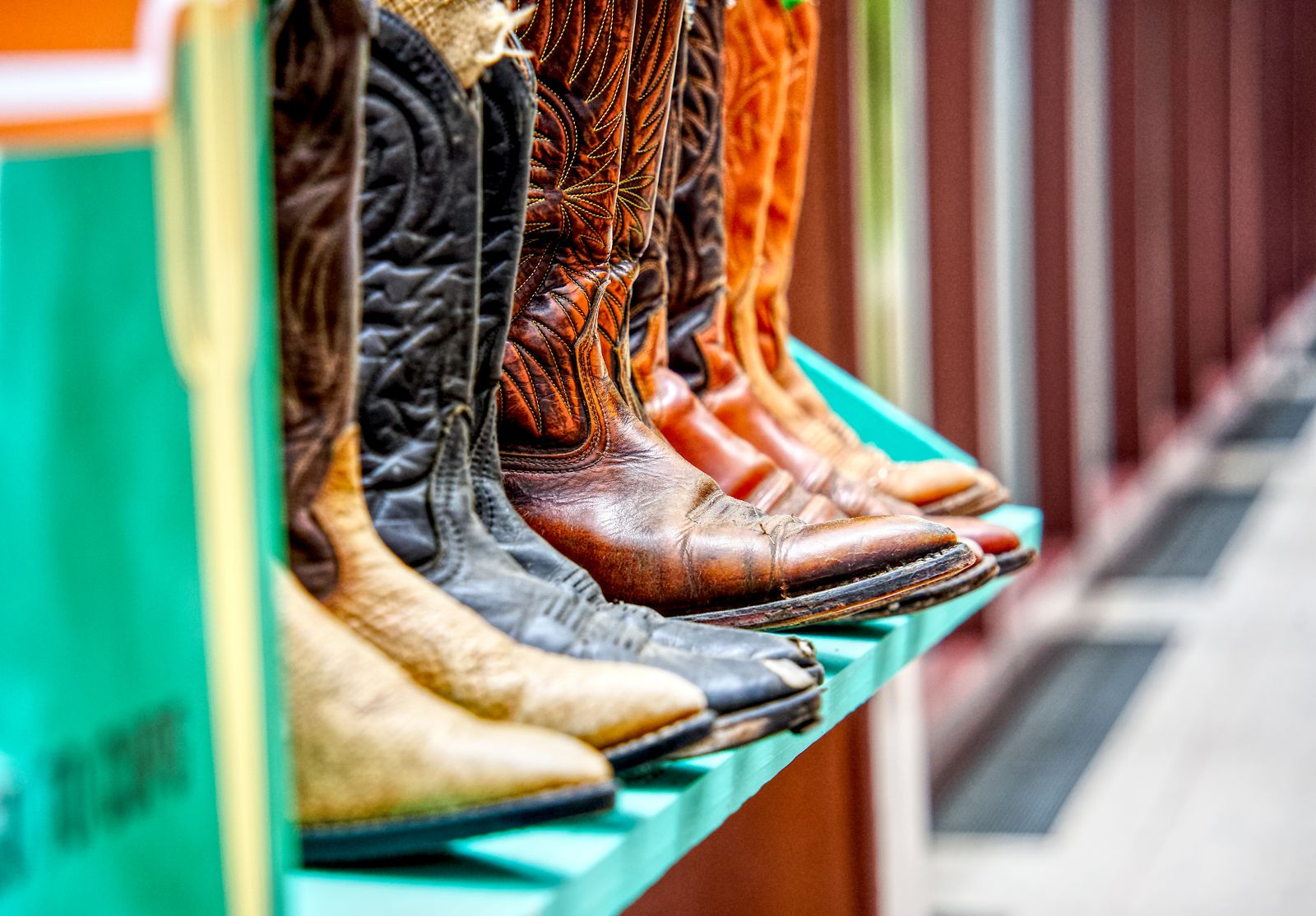 A colorful display of leather cowboy boots on a shelf, showcasing detailed craftsmanship — illustrative stock photo, not a photo of Sam's Shoe Service.