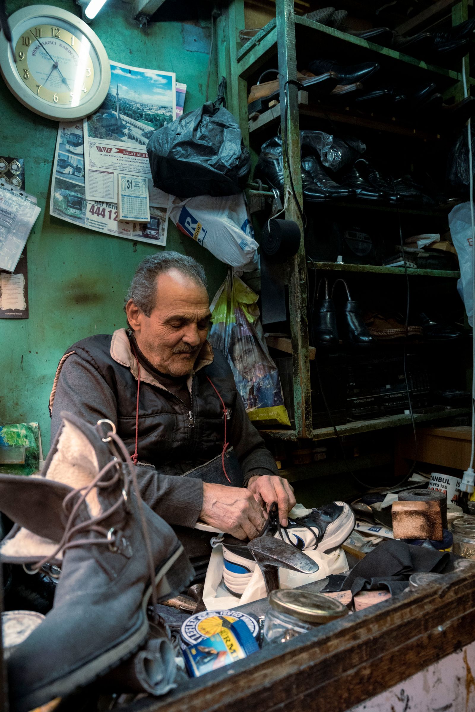 A cobbler at work repairing shoes at a workbench covered in tools — illustrative stock photo, not a photo of Sam's Shoe Service or its staff.