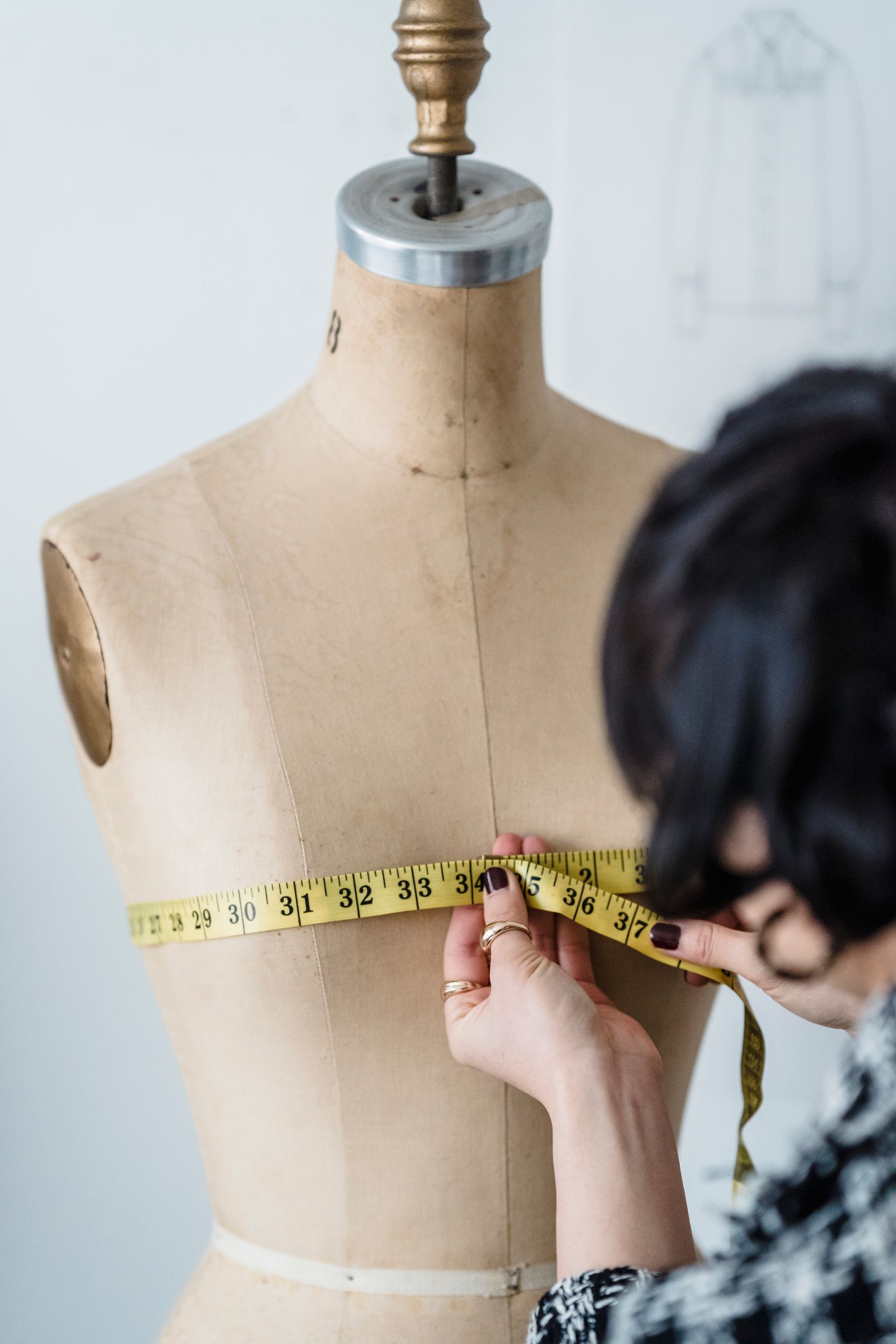 Illustrative stock photo of a tailor measuring a garment on a mannequin — not Silver Thimble's own shop or staff.