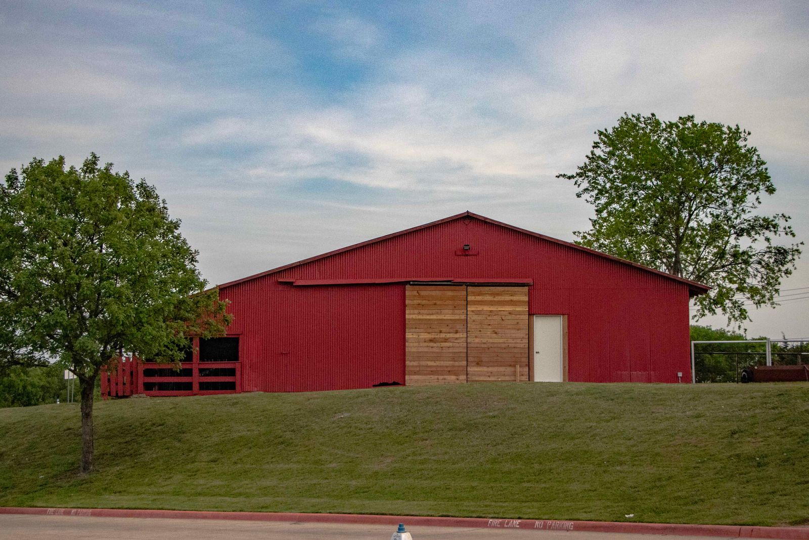 A red barn on a grassy hill surrounded by trees in rural Texas — illustrative stock photo representing the rural Grimes County service area, not a photo of an actual client property.