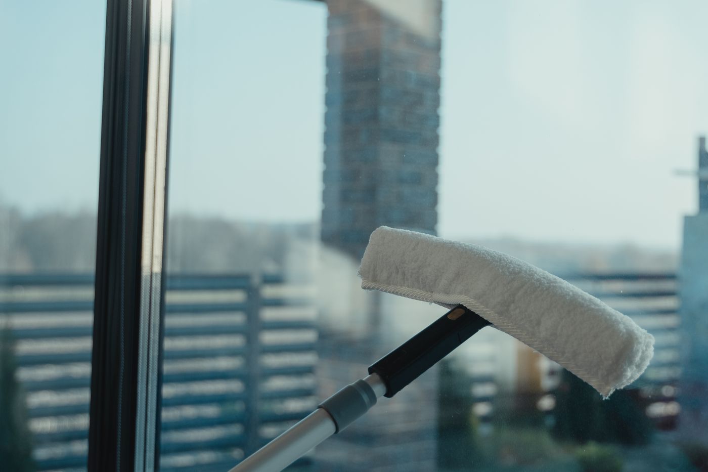 A cleaning tool being used on a large glass window with a clear outdoor view — illustrative stock photo, not Skyes View's own equipment.
