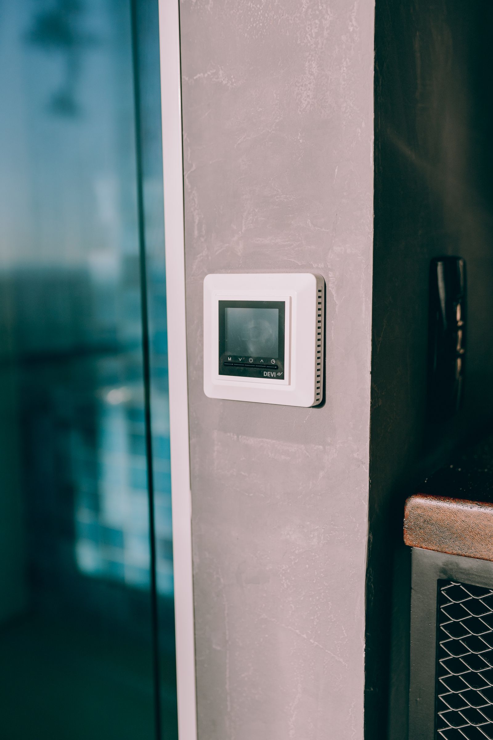 A digital thermostat mounted on an interior wall next to a window — illustrative stock photo, not a photo of Static Heating and Air Conditioning's work.